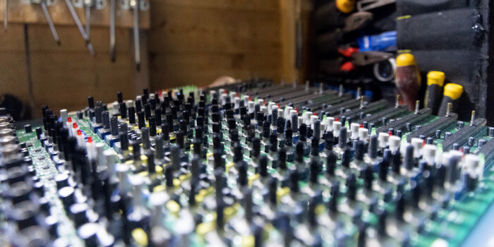 Close-up of hands connecting multiple audio cables into a rack-mounted patch panel.